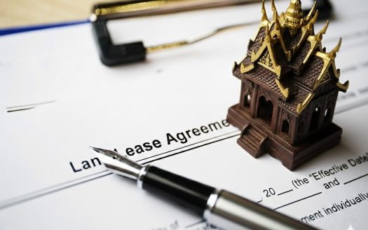 Land lease agreement document with a miniature Thai temple model and pen.