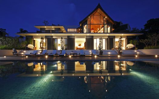 Elegant modern villa with illuminated pool and spacious outdoor area at night.