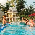 Family splashing in tropical resort swimming pool