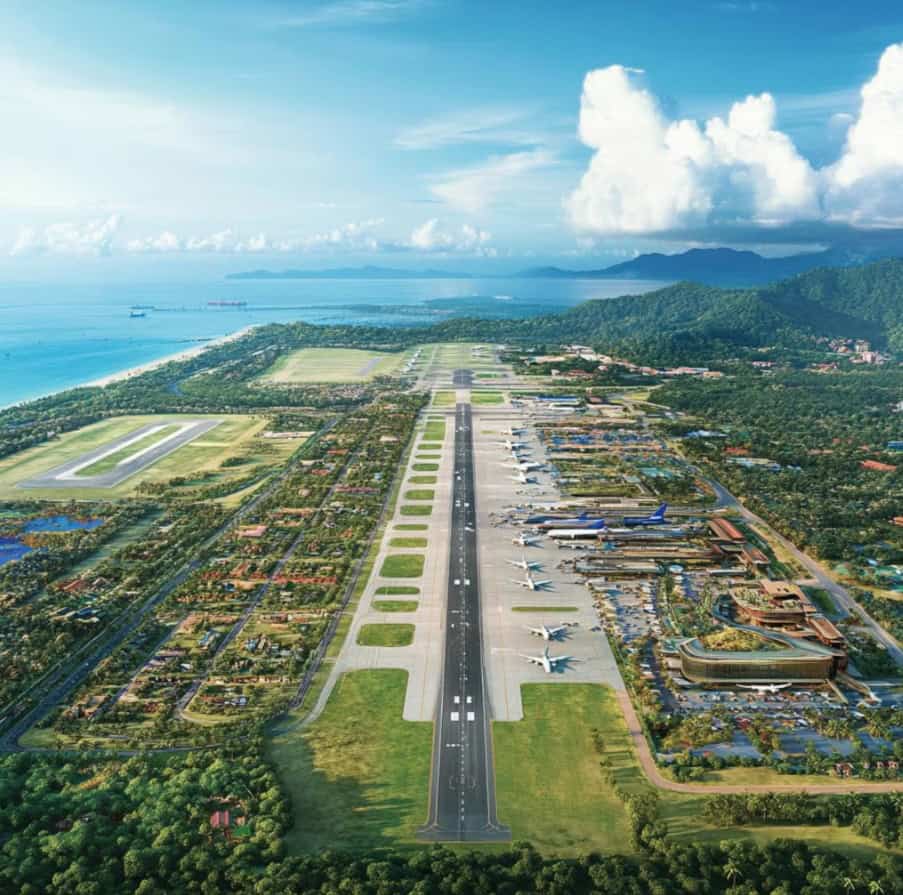Aircraft runway at an airport with surrounding greenery and ocean view.