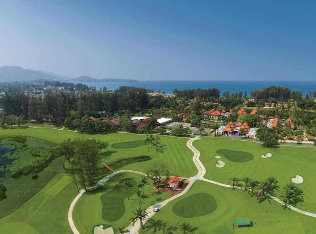 Golf course with ocean view and lush greenery in the background.