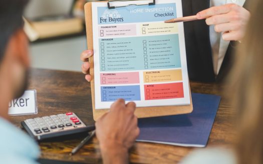 Estate agent showing home inspection checklist to buyer