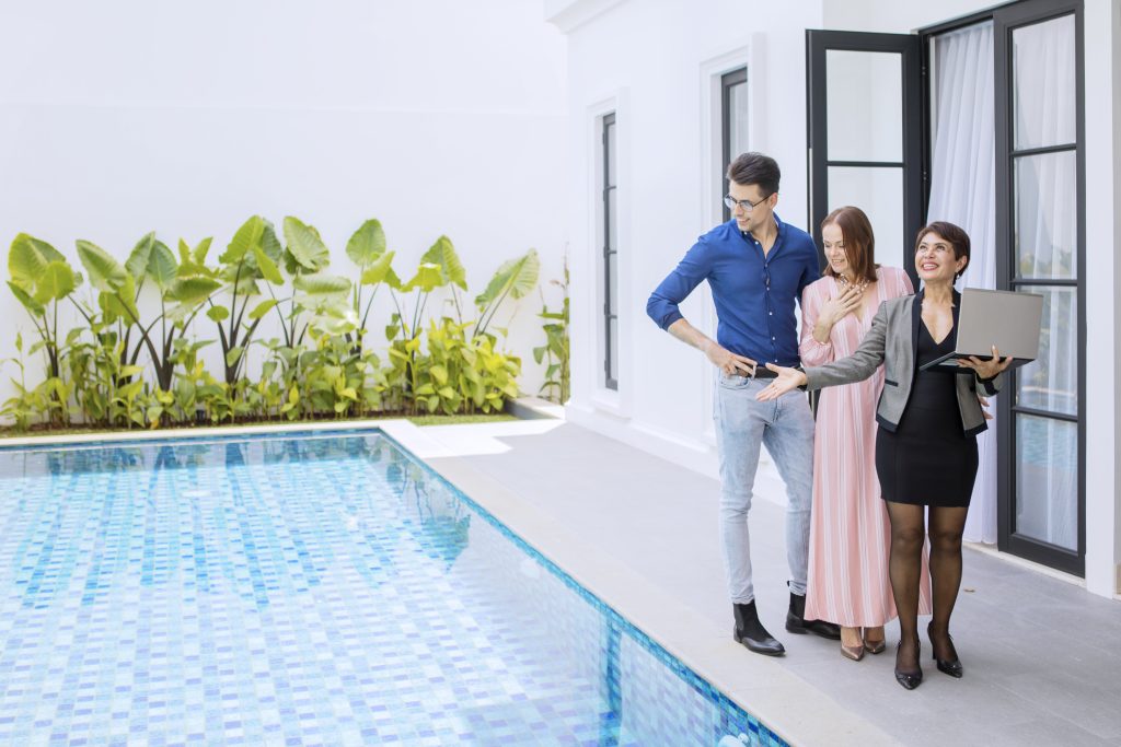 Estate agent showing couple modern home with pool