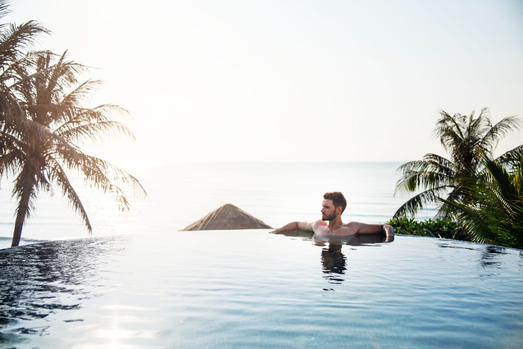 Man relaxing in infinity pool by ocean