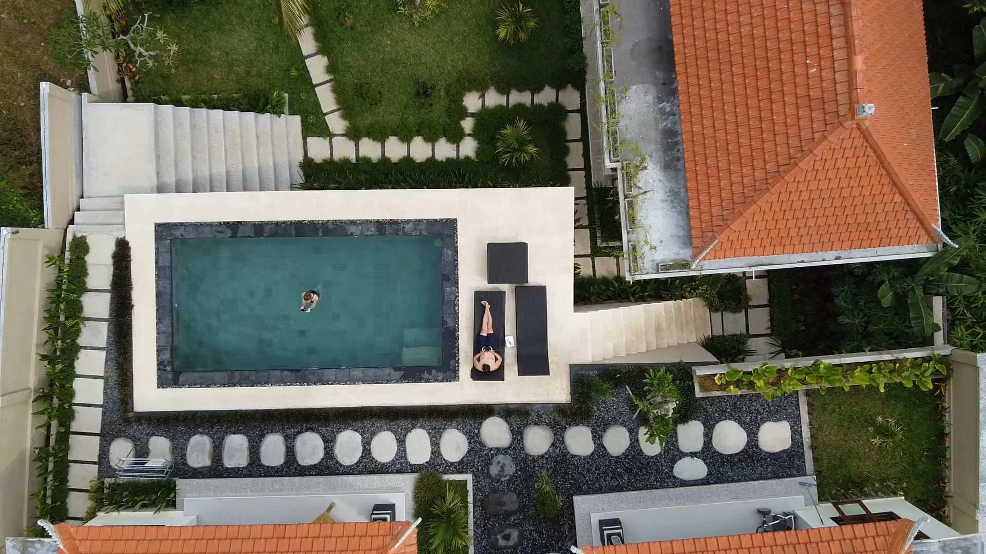 Swimming pool with garden and outdoor seating in a modern backyard setting.